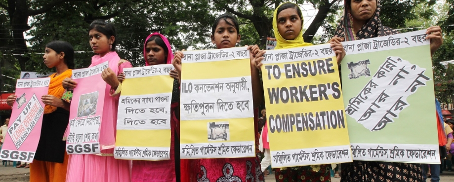 Young women workers hold up signs demanding compensation following the collapse of Rana plaza. Photo credit: Shutterstock/ Bayazid Akter.